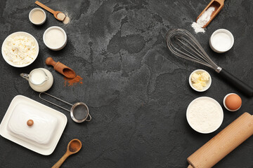 Different ingredients for preparing sweet cinnamon roll on black background