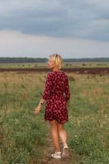 Portrait of a beautiful blonde girl in a red dress on a ranch.