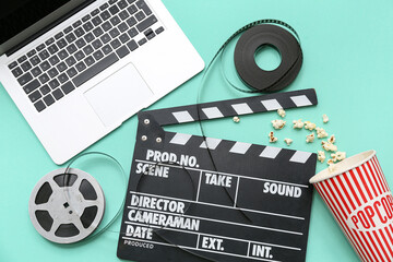Movie clapper with film reels, popcorn and laptop on turquoise background