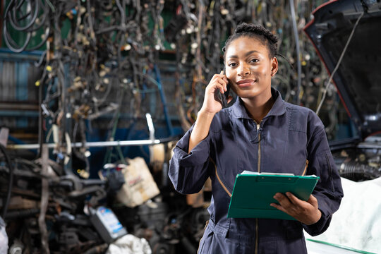 female worker or mechanic talking on smartphone with customer in garage - Powered by Adobe