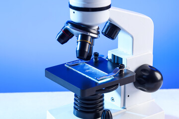 Modern microscope on blue background