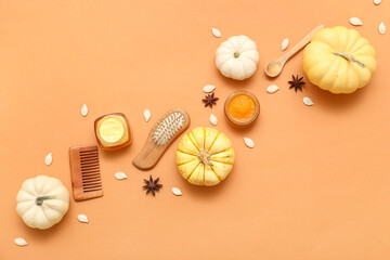 Jars of cosmetic products with pumpkin, hair comb and brush on orange background