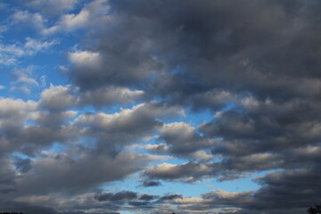 Obraz premium Dark and white clouds create a contrasting pattern against the blue sky.
