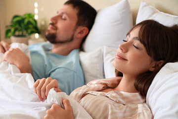 Young happy couple in pajamas sleeping together at home