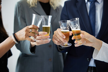 close up businesspeople clinking glasses and celebrating have a drink after work in the office