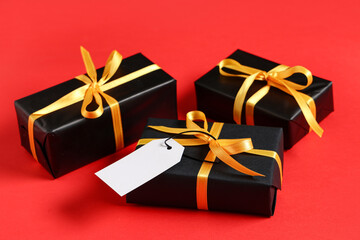 Black gift boxes with golden ribbon on red background