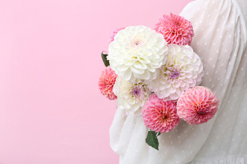 Woman with bouquet of beautiful dahlia flowers on pink background, closeup