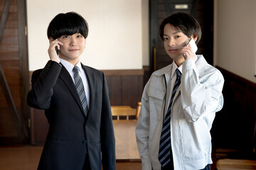 スマホを持ったスーツと作業服の男性
