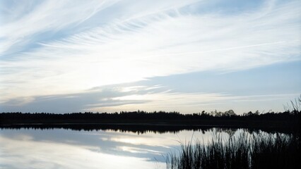 Obraz premium Calm Lake Reflecting the Sky on a Serene Cloudy Evening
