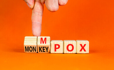 Monkey POX or Mpox symbol. Concept word Monkey POX or Mpox on wooden cubes. Doctor hand. Beautiful orange table orange background. Medical Monkey POX or Mpox concept. Copy space.
