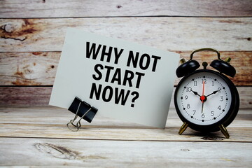 Why not start now? text on paper card with alarm clock on wooden background