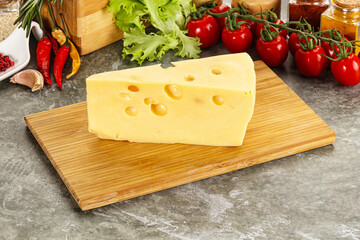 Swiss Maasdam cheese triangle over board