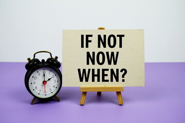 If Not Now. When? text on paper card with alarm clock on purple background