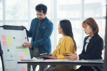 Strategic Business Meeting: A focused team collaborates around a whiteboard, brainstorming ideas and strategies for success. The image depicts a diverse team in a modern workspace.
