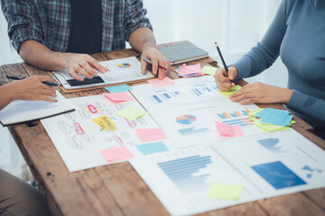 Collaborative Brainstorming: A team of professionals gather around a table, their hands reaching for sticky notes, representing a dynamic exchange of ideas and strategies.  