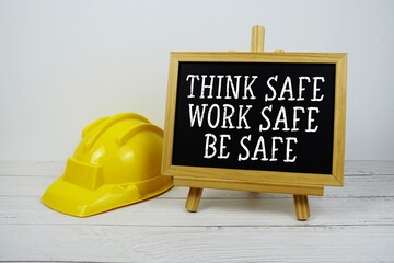 Think Safe Work Safe Be Safe text on blackboard with safety helmet on wooden background