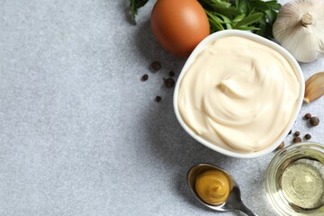 Bowl with mayonnaise and ingredients for cooking on gray background