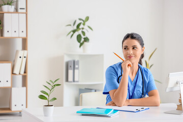 Young female medical student sitting at table in clinic