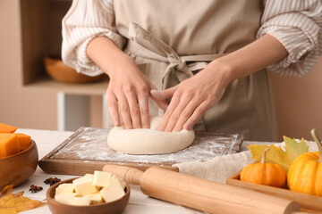 Woman preparing dough for tasty pumpkin strudel on table in kitchen