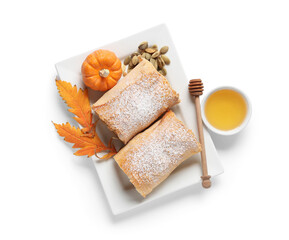 Plate with tasty pumpkin strudel, seeds and bowl of honey on white background