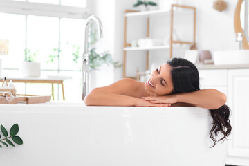 Obraz premium Beautiful young happy woman relaxing in bathtub at home