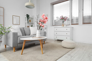 Sofa and coffee table with magnolia flowers in interior of living room