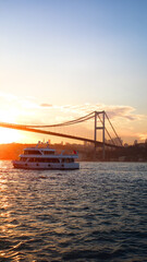 Sunset view of Bosphorus Bridge and ferry in Istanbul, for vertical wallpaper