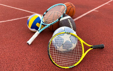 A variety of sports equipment including an american football, a soccer ball, a tennis racket, a tennis ball, and a basketball