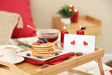 Tray with tasty breakfast for Valentine's Day on bed, closeup