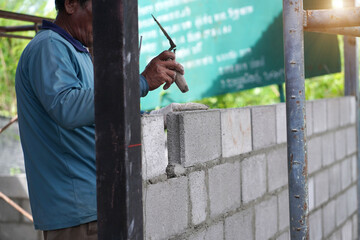 The builder places the block during the construction of the wall