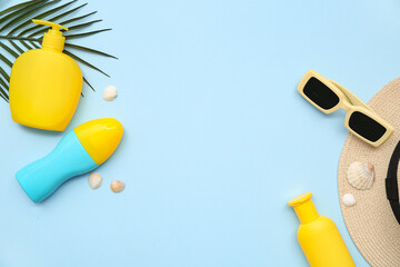 Composition with bottles of sunscreen cream, sunglasses, palm leaf and seashells on blue background