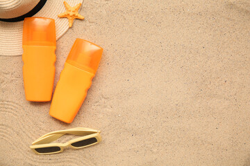 Starfish, hat, sunglasses and bottles of sunscreen cream on sand as background
