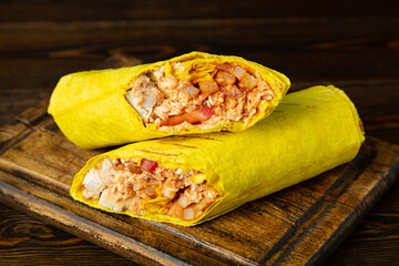 Shawarma, shaverma, doner with chicken and fresh vegetables on a wooden board on a wooden table.