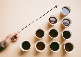 Person hand holding a cup of coffee takeaway surrounded by many coffee paper cup on clean background.drinking and refreshment.business inspiration ideas