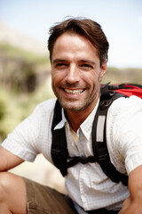 Relax, hiking and portrait of man on mountain with smile, pride and confidence on holiday adventure for travel. Break, happy face and hiker on hill with backpack, rest and outdoor vacation in nature