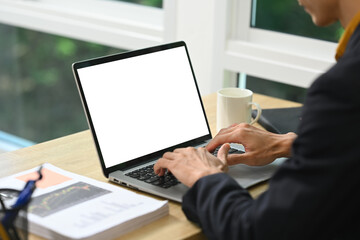 Businessman in suit working on laptop with blank screen for mockup