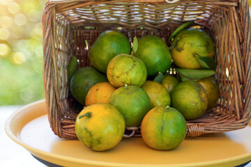 Pour clusters of oranges from the basket onto the yellow metal table surface.