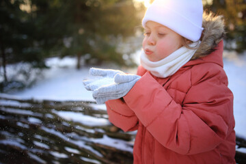 Obraz premium Winter Wonder: A Child Blowing Snowflakes from Their Hands