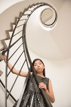 cute asian girl in dress on spiraliing staircase in building