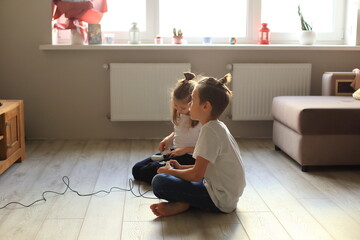 A lively scene of a boy and girl enthusiastically playing video games together at home. they...