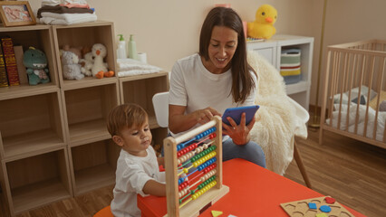 Woman using tablet with son sitting on bed in a cozy bedroom, showcasing family love and togetherness in a nurturing home environment.