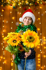 A teenage girl poses with sunflowers bouquet in New Year decorations with festive illumination and garlands, Christmas lights and decorations, Holiday theme