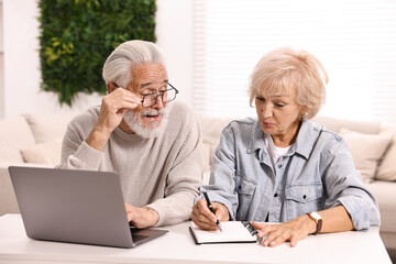 Fototapeta premium Pension savings. Senior couple planning budget at white table indoors