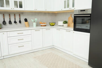 Stylish soft rug on wooden floor in kitchen