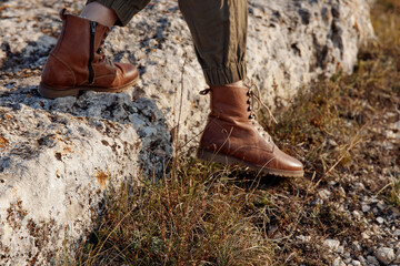 Brown boots resting on stone wall in the serene field, tranquil travel vibes, nature exploration...