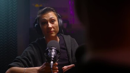 Androgyne girl is a guest on the podcast. A lesbian woman talks, moves the microphone, listens to the speaker's speech. They discuss psychology and LGBT issues on a radio show. Female butch