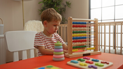 Toddler boy playing with educational toys at kindergarten table in bright indoor setting