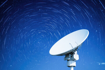 Obraz premium Satellite dish against swirling star trails, illustrating communication technology and cosmic exploration. Long exposure image. 