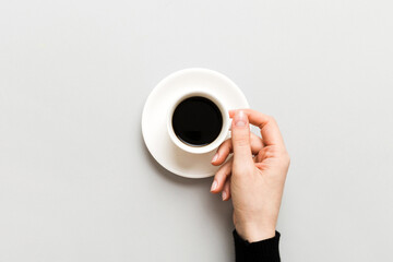 Minimalistic style woman hand holding a cup of coffee on Colored background. Flat lay, top view...