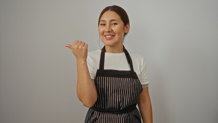 Young hispanic woman wearing apron smiling and pointing to the side over isolated white background